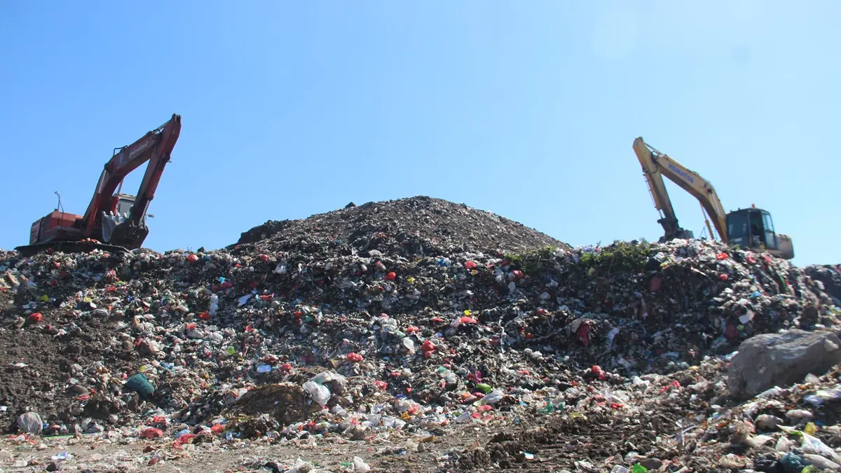 MENGGUNUNG: Dua alat berat mengurai gunungan sampah di TPA Banjardowo, Jombang, Rabu (15/7). (Anggi Fridianto/Radar Jombang)
