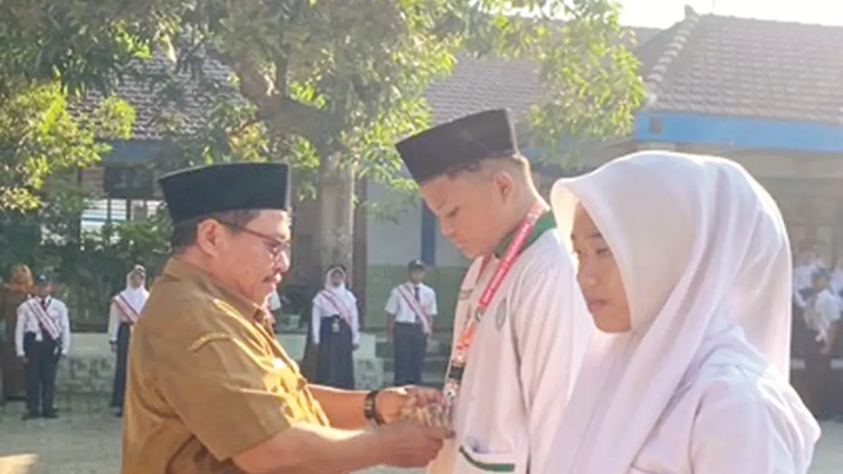 SEMANGAT: Kepala SMPN 2 Mojoagung, Jombang, Sugeng Wibowo MPd, menyematkan tanda peserta MPLS kepada siswa baru, Senin (13/7). (Wenny Rosalina/Radar Jombang)
