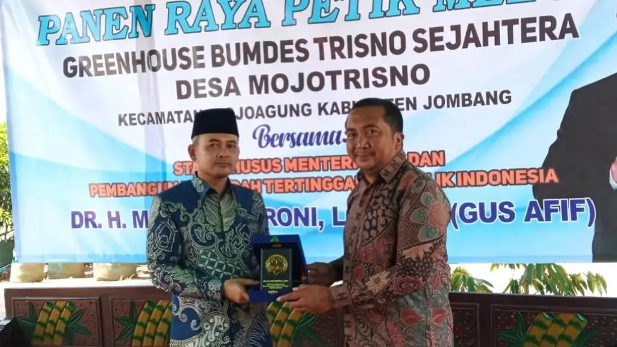 APRESIASI: Staf Khusus Menteri Desa dan PDT RI, Dr HM Afif Zamroni Lc MEI (Gus Afif) memberikan cenderamata kepada Kepala Desa Mojotrisno, Mojowarno, Jombang, Nanang Sugiarto saat kunjungan panen raya petik melon di Greenhouse BUMDes Trisno Sejahtera, Sabtu (25/7). (Dwi Aris/Radar Jombang)