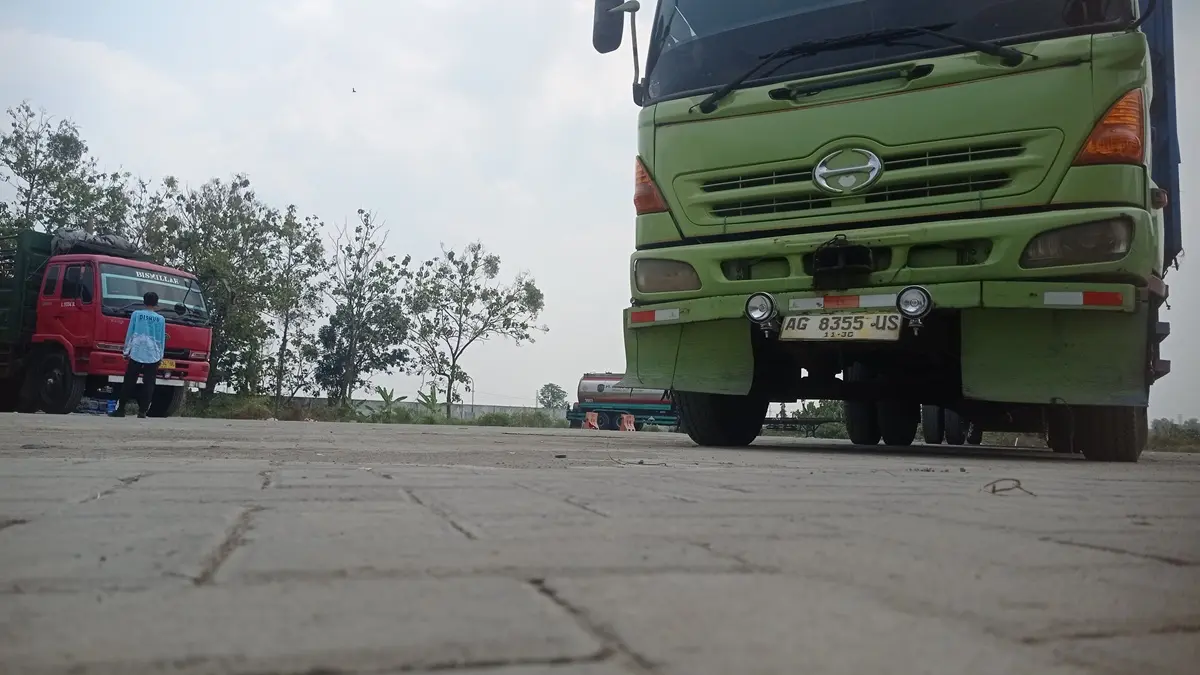 SUMBANG PAD: Salah satu petugas berada di antara kendaraan angkutan barang yang terparkir di Desa Glagahan, Kecamatan Perak, Jombang. (Ainul Hafidz/Radar Jombang)