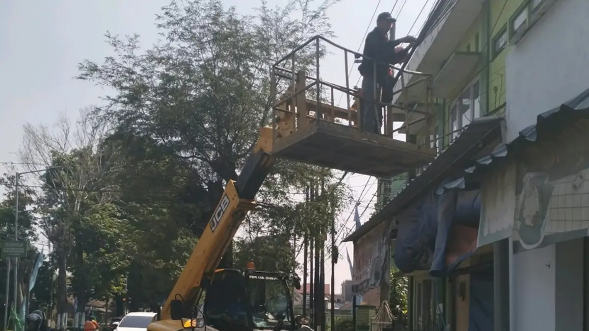 DIRAPIKAN: Petugas merapikan kabel semrawut di area PP Bahrul Ulum Tambakberas, Desa Tambakrejo, Kecamatan Jombang. (Ainul Hafidz/Radar Jombang)