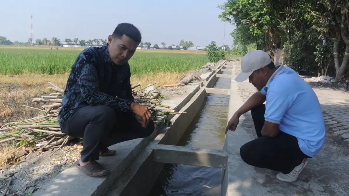 LANCAR: Sekdes Sumberagung, Kecamatan Peterongan, Jombang Haris Andi Lesmono (kiri) dan Dwi Handoko, Kaur Perencanaan Sumberagung, menunjukkan bangunan jaringan irigasi di Dusun Banjaranyar. (Dwi Aris/Radar Jombang)