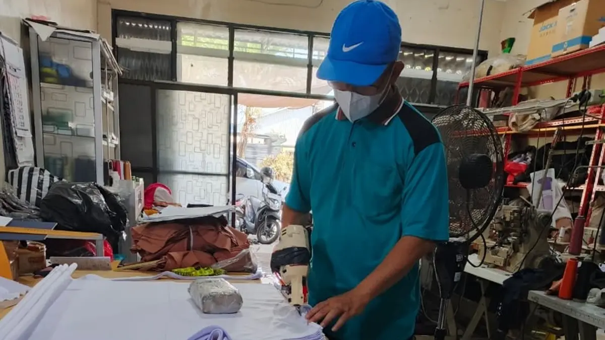 TELITI: Penjahit di Desa Plosogeneng Kecamatan Jombang sedang melakukan pemotongan kain seragam siswa. (Wenny Rosalina/Radar Jombang)
