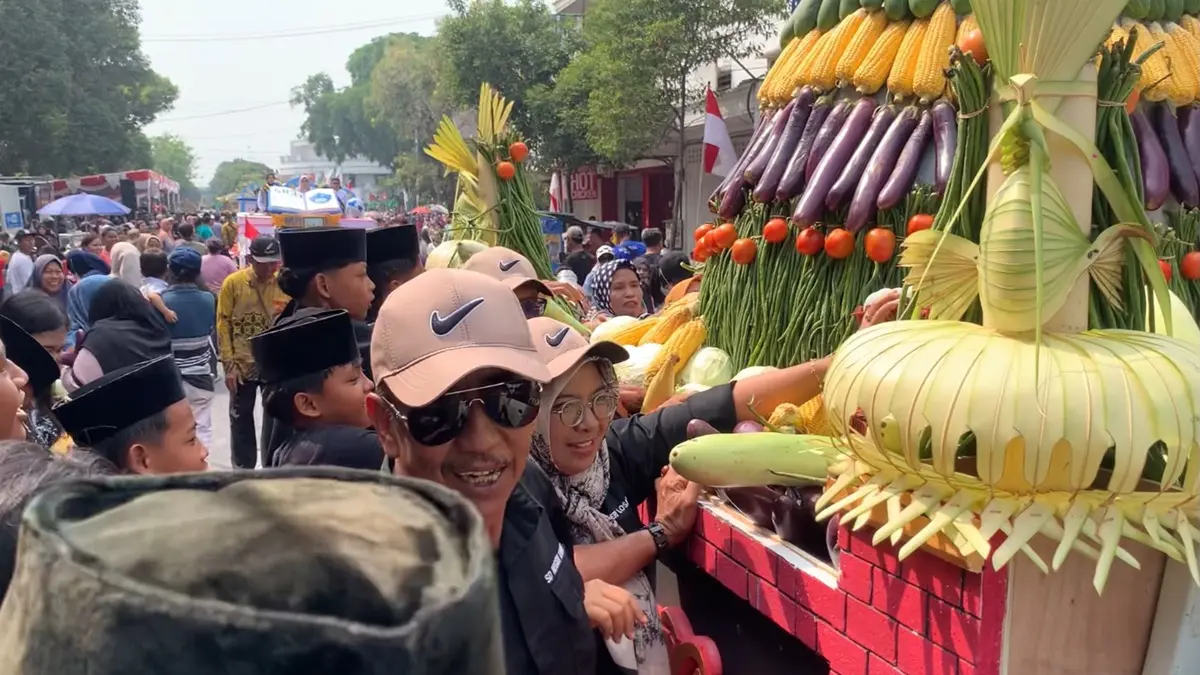 Warga berebut gunungan hasil bumi dalam Karnaval Mobil Hias dan Hasil Bumi di Jl A Yani, Jombang, Sabtu (22/8). (Ainul Hafidz/Radar Jombang)
