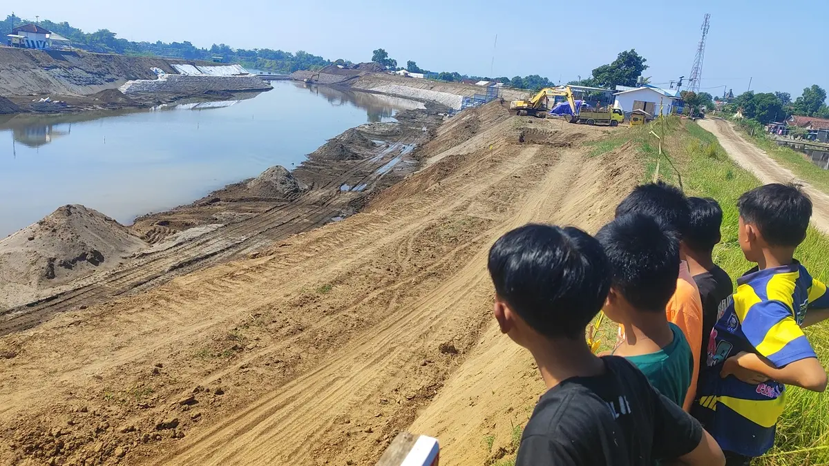 DIKERUK: Tanggul Sungai Brantas sisi selatan Desa Sudimoro, Kecamatan Megaluh, Jombang dijadikan saluran pengelak untuk proyek rehab Bendung Jatimlerek. (Ainul Hafidz/Radar Jombang)