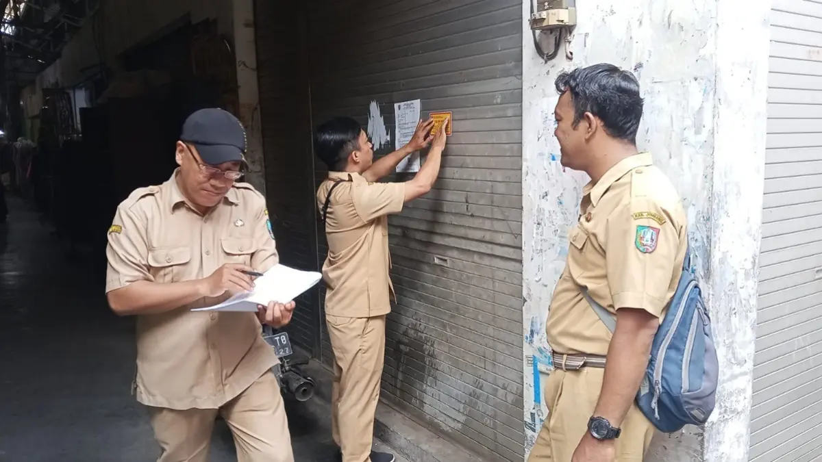 DISEGEL: Petugas menempel stiker segel di kios Pasar Mojoagung, Jombang, Selasa (1/9). (Ainul Hafidz/Radar Jombang)