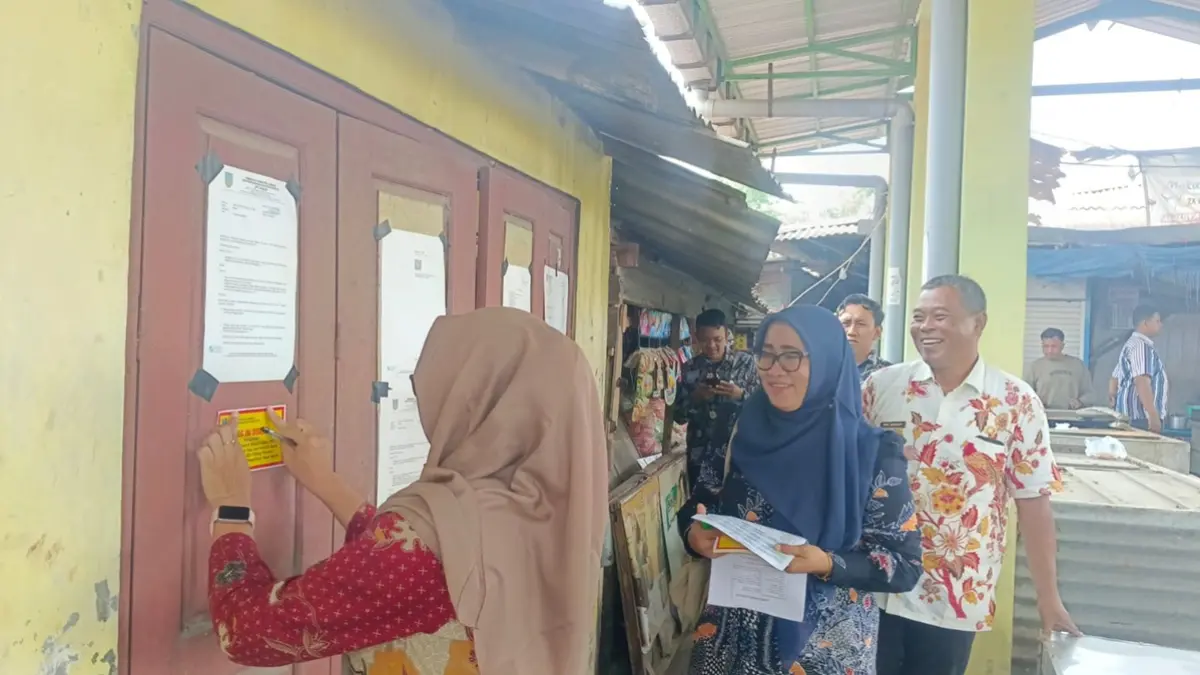 DISEGEL: Petugas memasang stiker segel di salah satu kios Pasar Sumobito, Jombang yang mangkrak dan menunggak retribusi, Kamis (3/9). (Ainul Hafidz/Radar Jombang)