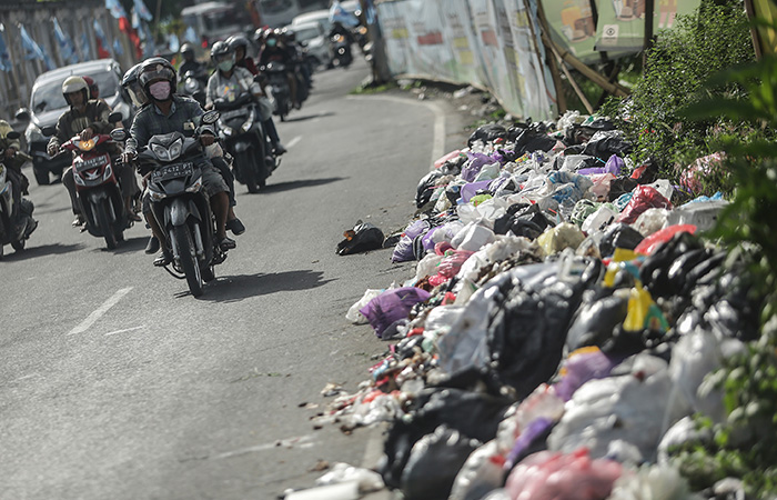 ELANG KHARISMA DEWANGGA/RADAR JOGJA  MENUMPUK: Pengendara motor melintas di samping tumpukan sampah yang memenuhi badan Jalan Kusumanegara kawasan Jomblangan, Banguntapan, Bantul Sabtu (13/1).