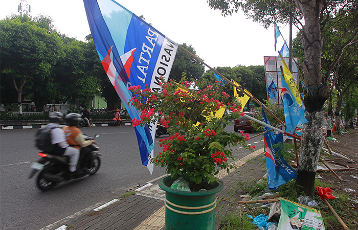 TIDAK SESUAI: Pengendara kendaraan bermotor melintas di dekat alat peraga kampanye (APK) caleg dan bendera parpol yang terpasang di trotoar kawasan Stadion Kridosono Selasa (30/1).