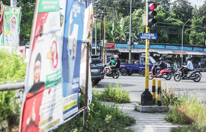 SAMPAH VISUAL: Kendaraan bermotor melintasi deretan APK yang masih terpasang di kawasan simpang empat Sagan, Caturtunggal, Depok, Sleman kemarin (13/2).