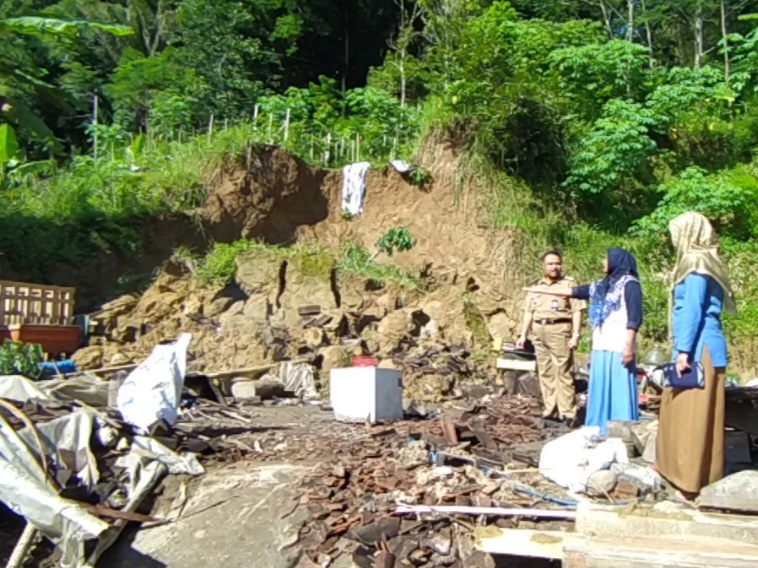 LONGSOR: Warga setempat tengah melakukan kerja bakti terhadap rumah yang longsor pada Minggu (25/2).