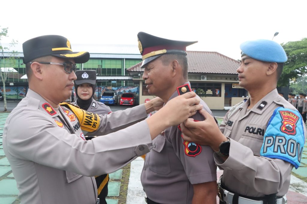 PENGHARGAAN: Wakapolres Purworejo Kompol Fadli saat menyematkan tanda pangkat baru ke bahu seorang personel Polres Purworejo dalam upacara kenaikan pangkat di halaman Mapolres Purworejo, Jumat (1/3).