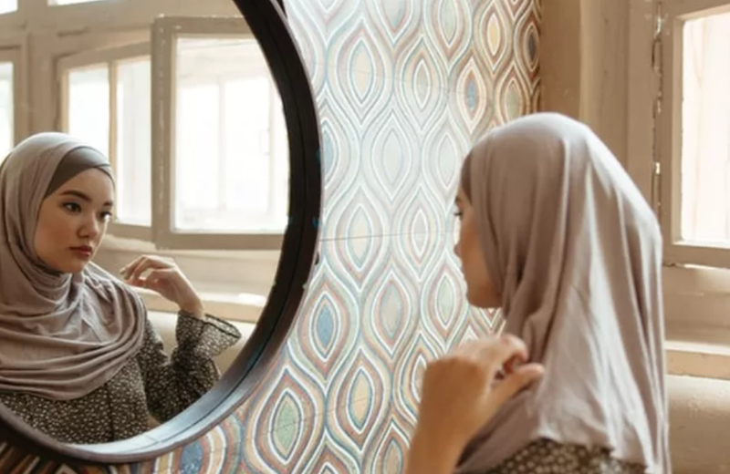 Illustrasi perempuan muslim bercermin.