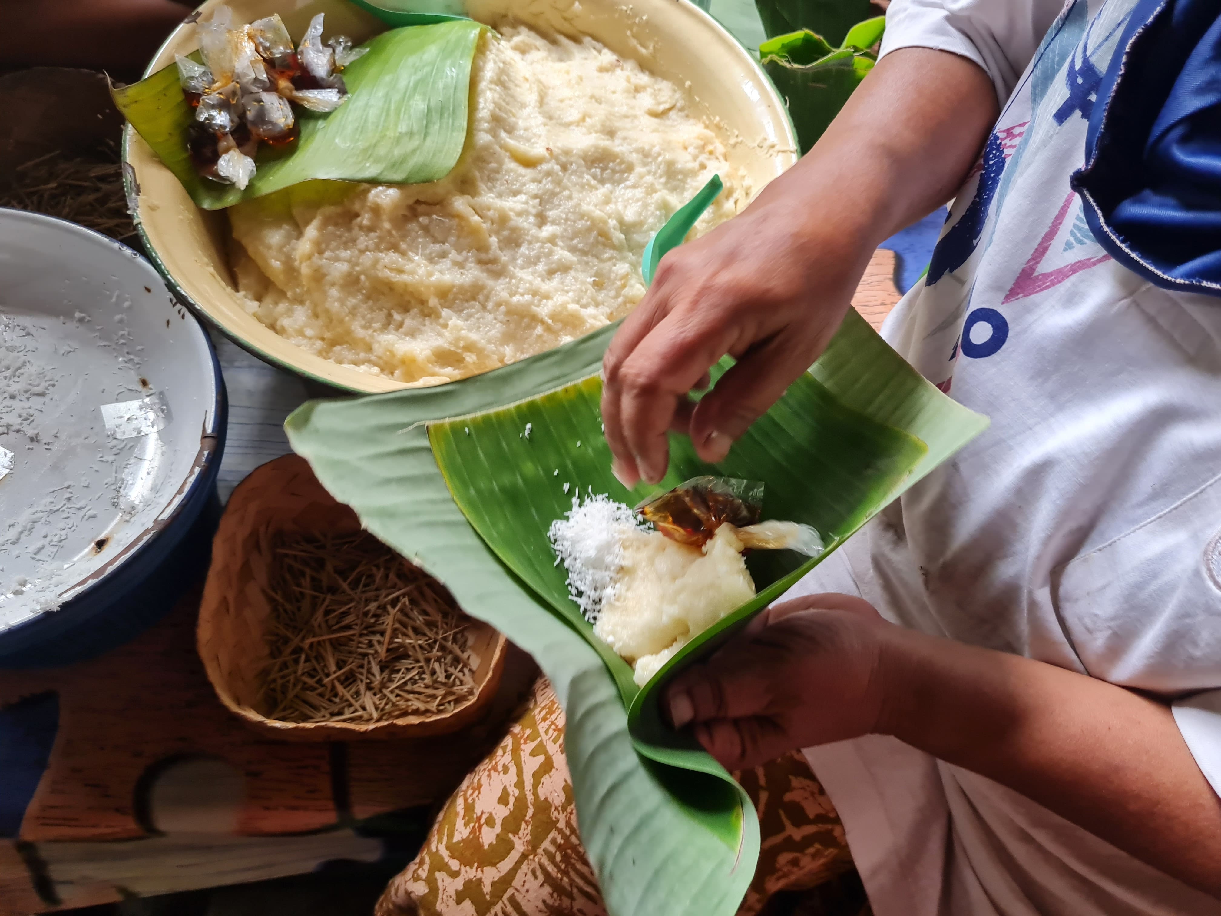 TELATEN: Usai ditumbuk, Poningsih bersama Kasmirah mulai membungkus jemunak dengan daun pisang. Di dalamnya dilengkapi parutan kelapa dan gula merah cair.