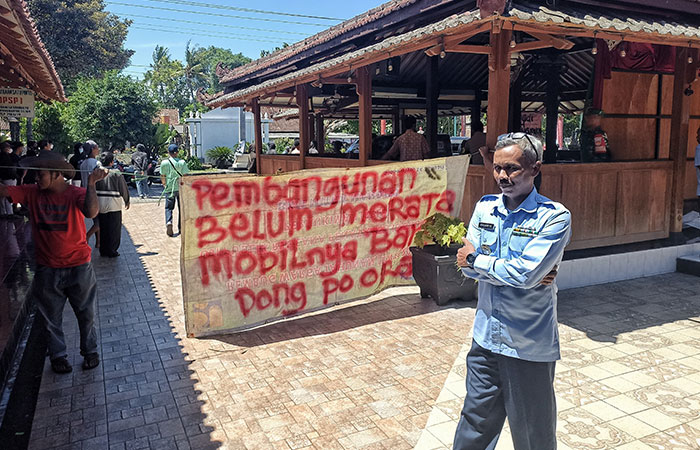 UNJUK RASA: Warga Kalurahan Sidomulyo membentangkan spanduk protes di hadapan Lurah Sidomulyo di Kantor Kalurahan Sidomulyo, Bambanglipuro, Bantul kemarin (19/3).
