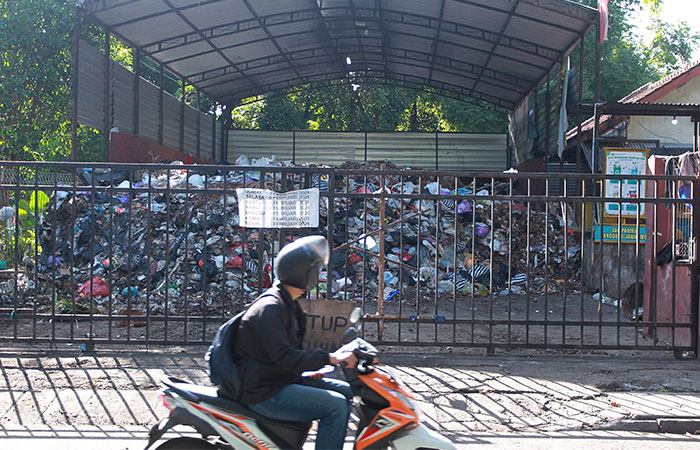 MENUMPUK: Pengguna jalan melintas di depan depo sampah barat Stadion Mandala Krida yang kondisinya sudah penuh (21/2). Untuk mengurangi sampah dalam menyambut pemudik, delapan depo sampah akan dikoson