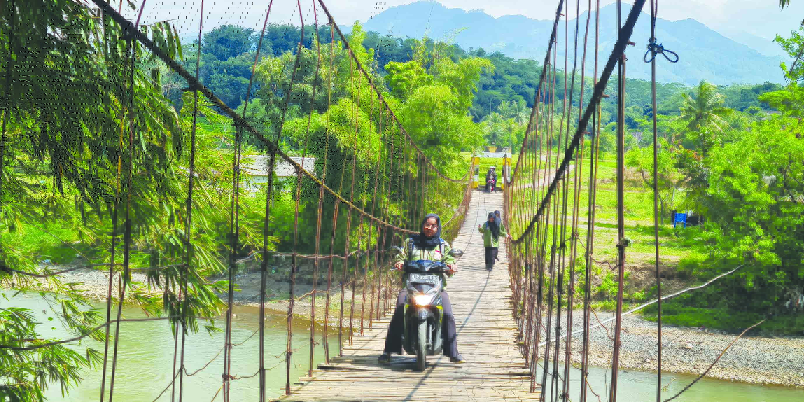 KURANG LAYAK: Warga melintas di jembatan gantung yang menghubungkan Ngembik Lor, Kramat Utara, Kota Magelang dengan Rejosari, Bandongan, Kabupaten Magelang. (NAILA NIHAYAH/RADAR JOGJA)
