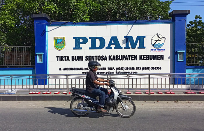 PERUSAHAAN DAERAH: Pengendara sepeda motor melintas di depan plang kantor PDAM Tirta Bumi Sentosa di Jalan Arungbinang, Kebumen.