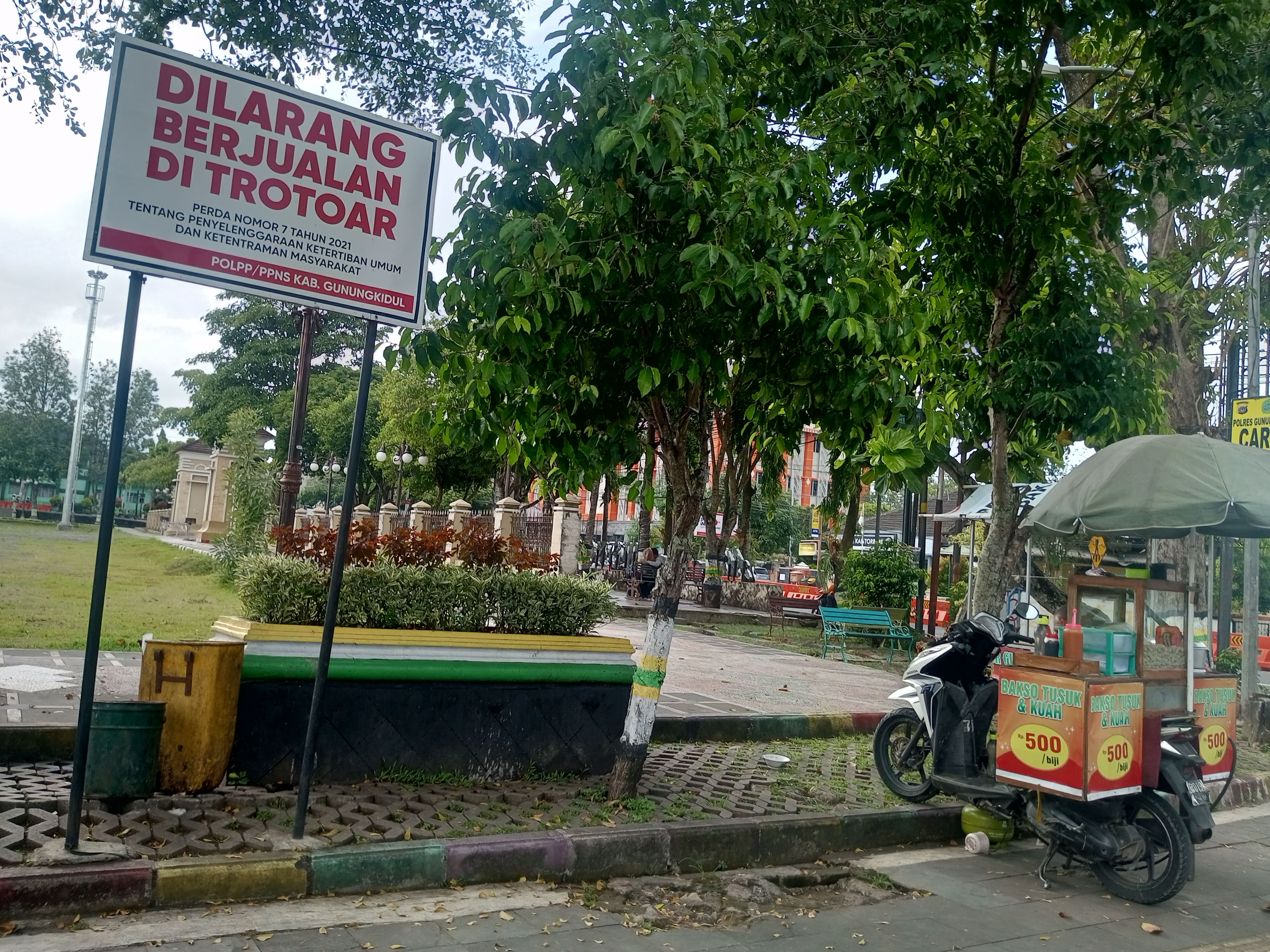 PKL Berjualan di sebelah Palang Peringatan Dilarang Berjualan di Trotoar sepanjang Alun-alun Wonosari.