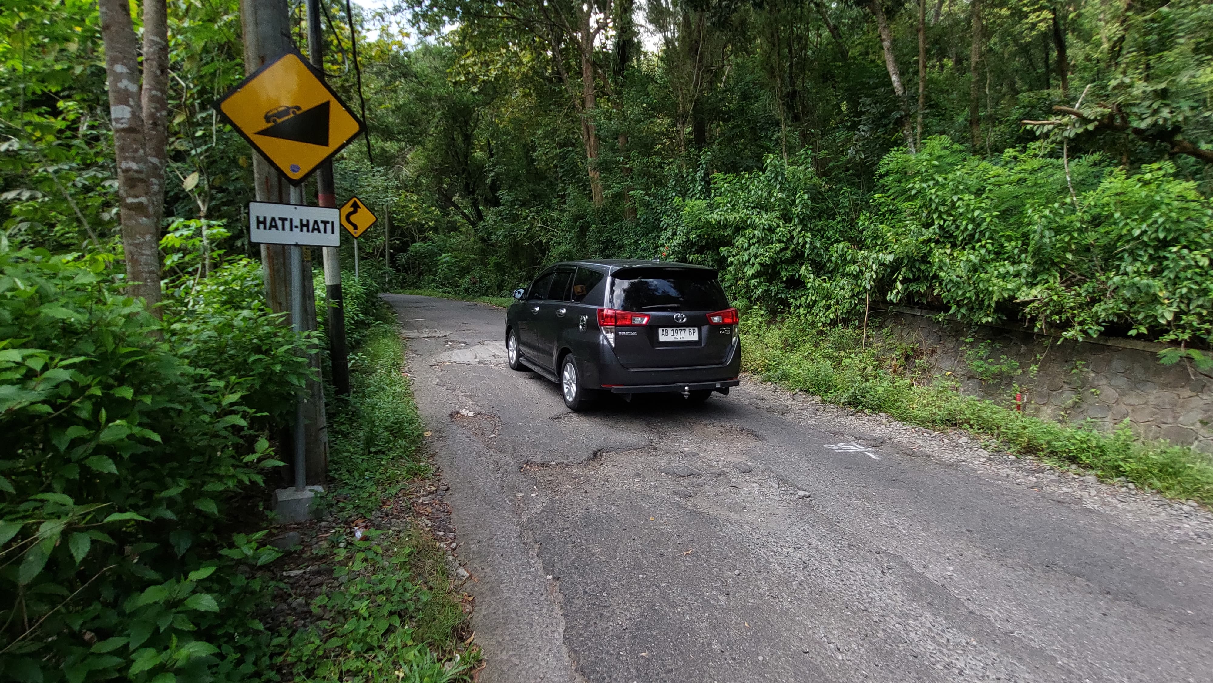 Kendaraan memelankan kecepatan saat melewati jalan berlubang di Waduk Sermo.