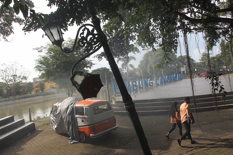 Warga melintas di dekat lampu hias yang kondisinya rusak di area Embung Langensari, Kota Jogja.