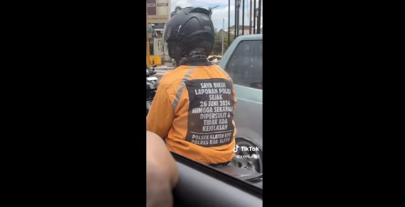 Seorang pengendara sepeda motor mengenakan jaket bertuliskan curhatan soal laporan ke Polsek Klaten.