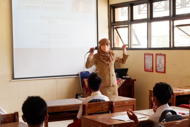 Ilustrasi guru sedang mengajar di kelas.