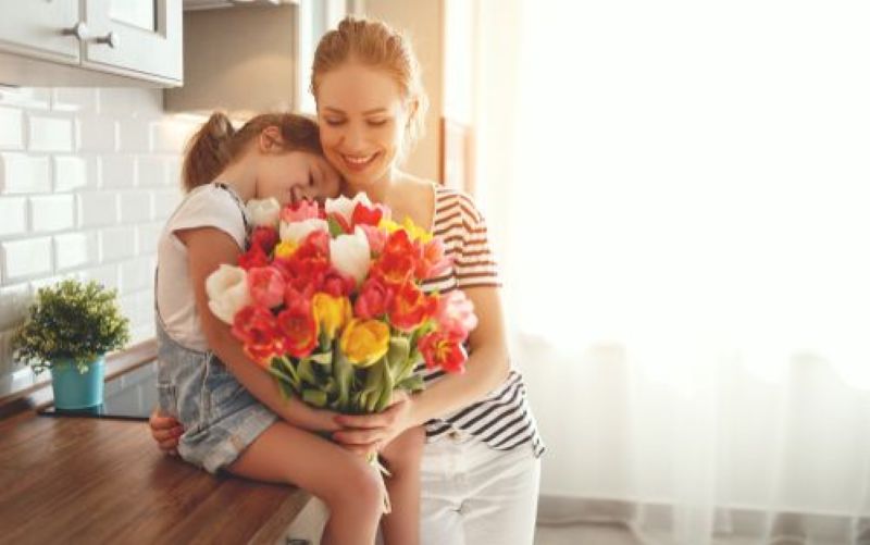 Seorang anak memberikan bunga kepada ibunya, tepat di Hari Ibu.