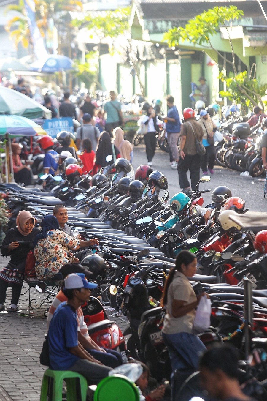 Wisatawan melintas di Jalan Pabringan yang dijadikan sebagai lokasi parkir sepeda motor dan mobil di Kota Jogja, Jumat (2/1/2026).