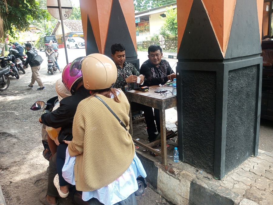 Petugas Pos TPR Baron sedang melakukan transaksi tiket restribusi wisata.