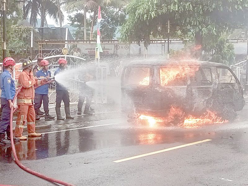 EVAKUASI: Petugas damkar berupaya memadamkan api yang membakar mobil Suzuki Carry di Jalan Jenderal Sudirman Rabu (14/1).