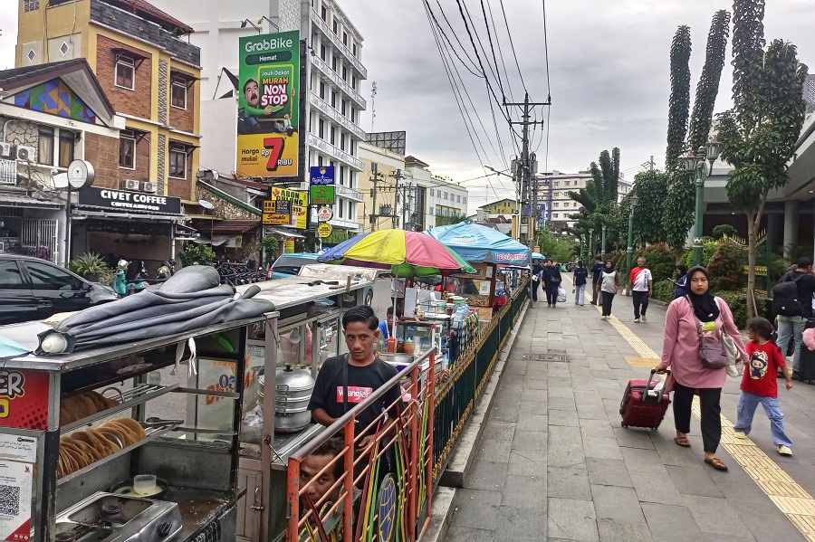 Pedagang kaki lima (PKL) berjualan makanan dan minuman di Jalan Pasar Kembang, tepat di sisi selatan Stasiun Tugu Jogja, Rabu (21/1/2026).
