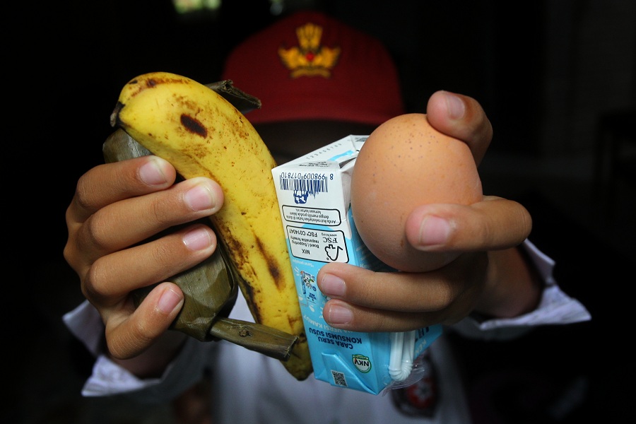 Siswa sekolah dasar menunjukkan menu Makan Bergizi Gratis (MBG) edisi Ramadan untuk dibawa pulang berupa arem-arem, pisang, susu kemasan, dan telur rebus, di Kota Jogja, Senin (23/2/2026). 