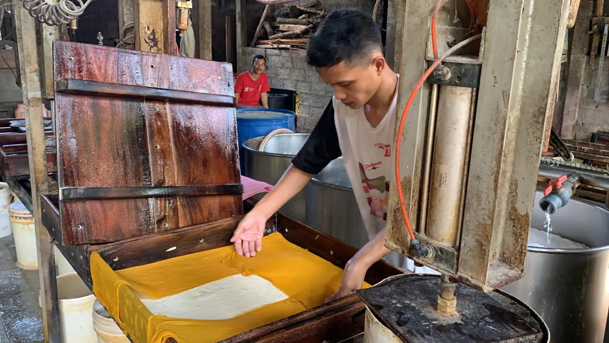 Perajin tahu di Kalurahan Tuksono mencetak tahu dengan alat pres lalu dipotong menjadi beberapa bagian.
