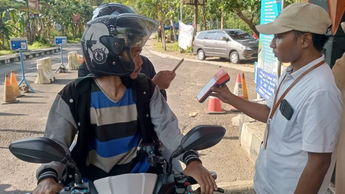 DIGITALISASI: Wisatawan sedang memotret kode transaksi tiket retribusi pada mesin Empos di Pos TPR Baron. (Yusuf Bastiar/Radar Jogja)
