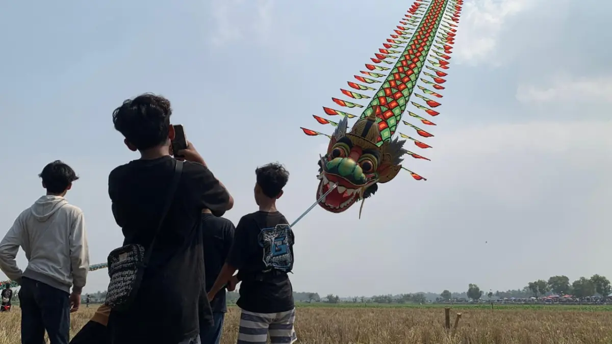 Peserta festival layang-layang mencoba menerbangkan layang-layang tipe train dragon.