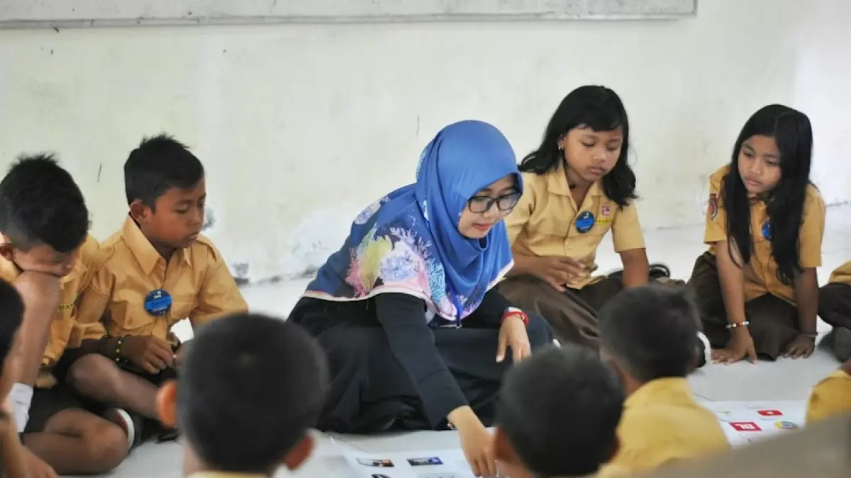 Seorang guru sedang menjelaskan pembelajaran kepada murid-muridnya di kelas dengan formasi forum group discussion. (Unsplash)
