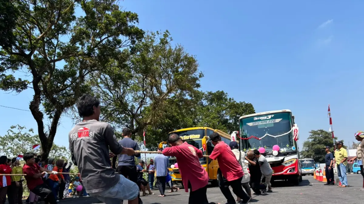 Masing-masing tim mengerahkan tenaganya untuk menarik bus agar sampai di garis finis, Kamis (13/8).