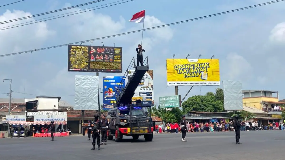 KHIDMAT: Anggota Brimob DIY sedang mengibarkan bendera merah putih di atas rantis saat pembacaan teks proklamasi di Simpang Giwangan Senin (17/8).&nbsp;(Cintia Yuliani/Radar Purworejo)