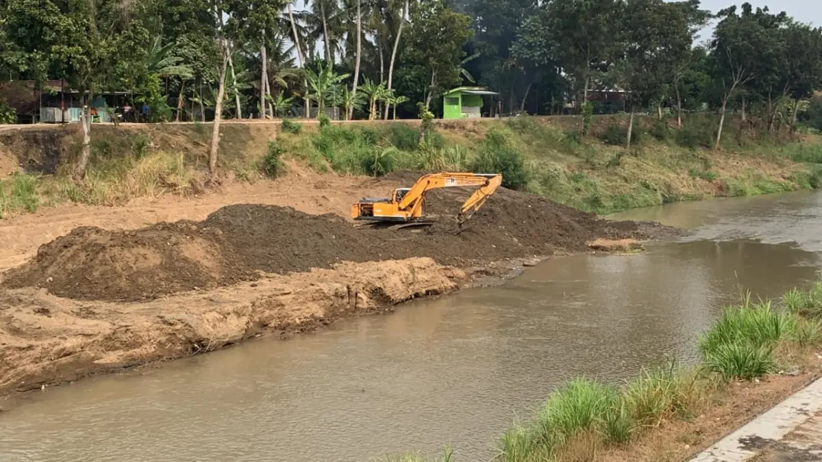 Alat berat excavator dan truk hilir mudik mengangkut tanah sedimentasi Sungai Serang.