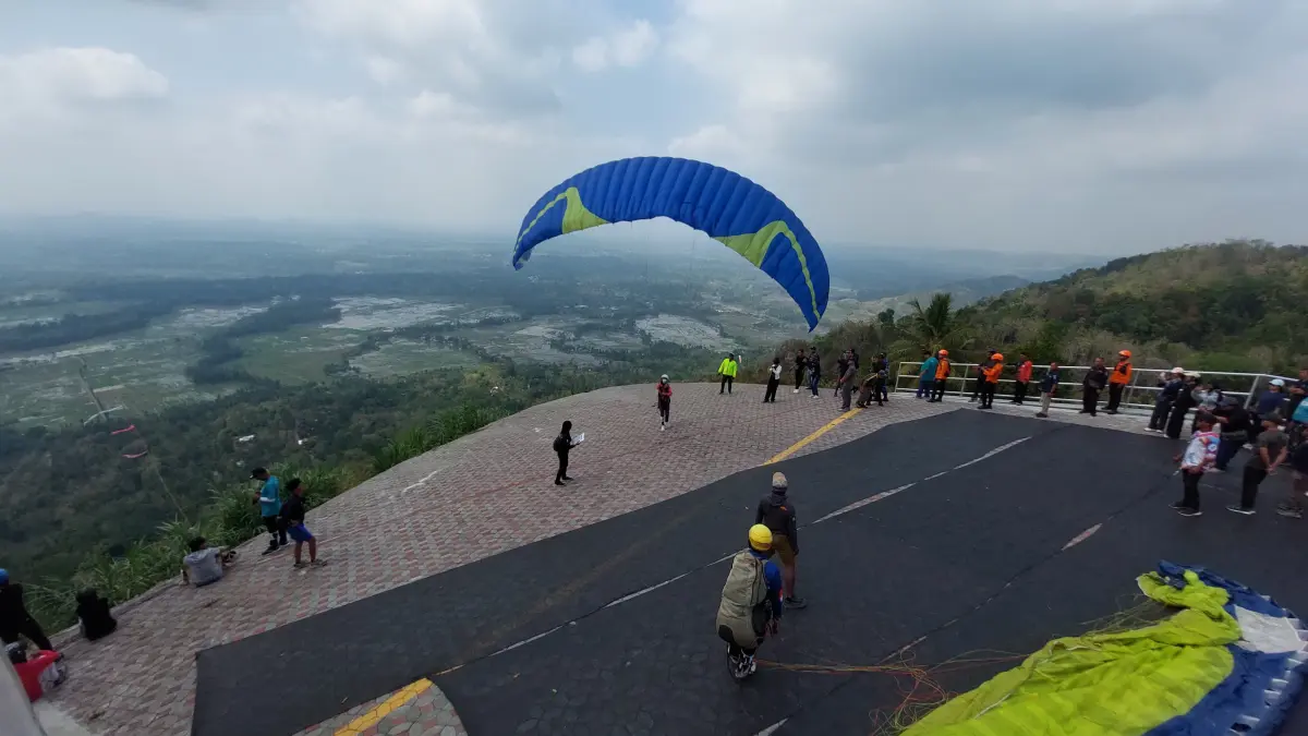 Atlet paralayang mengembangkan parasut di landasan Objek Wisata Giri Sembung.