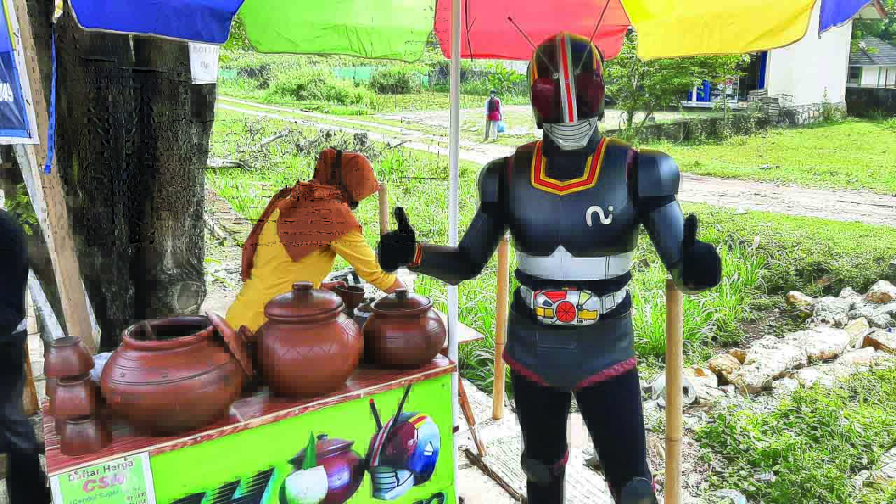 Penjual cendol dawet, Wahyu Prasetya,37, berakting dengan kostum Ksatria Baja Hitam di Jalan Semin- Karangmojo, tepatnya wilayah Kalurahan Jatiayu kemarin (23/6).
