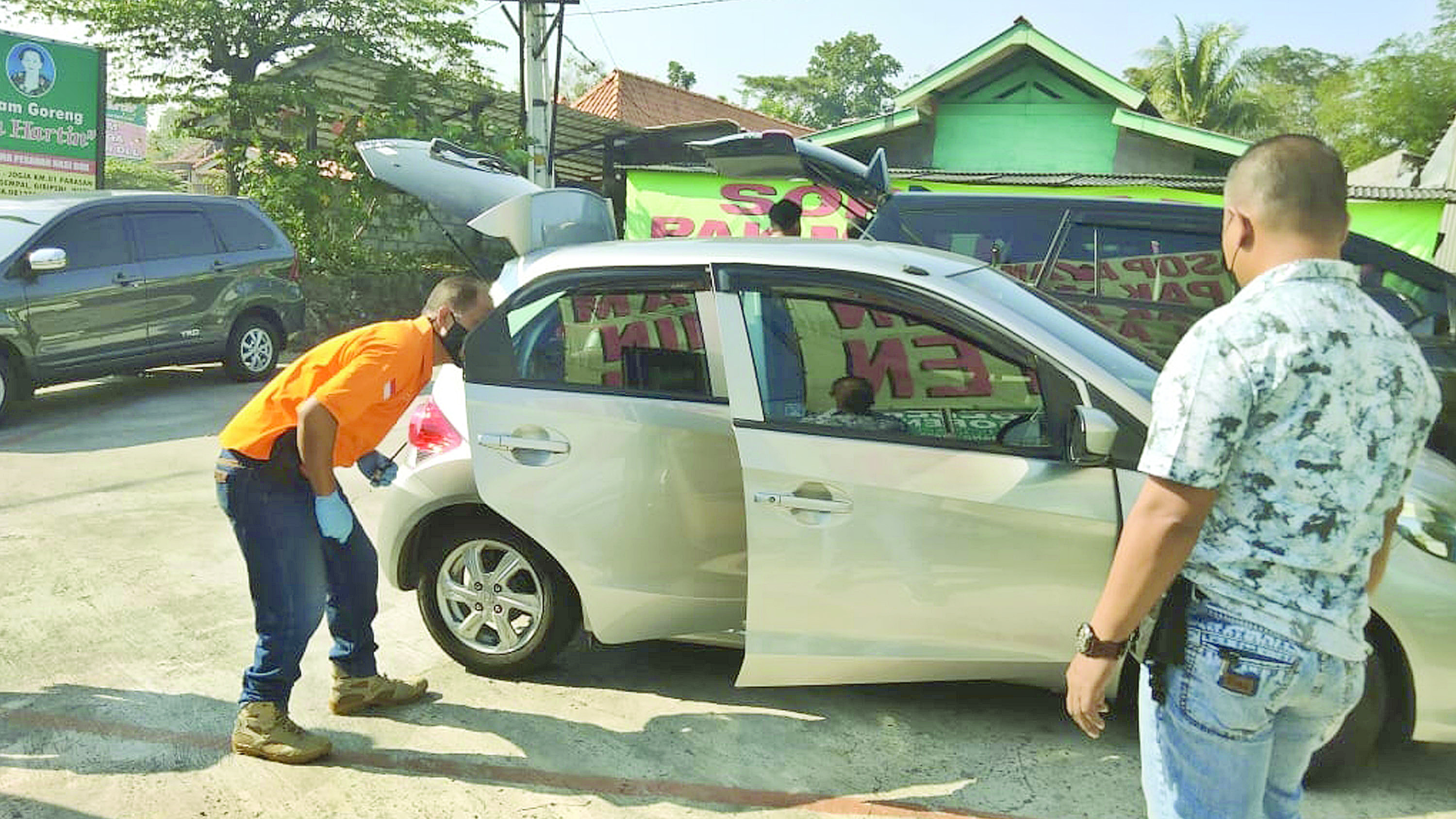 Aparat kepolisian tengah memeriksa kendaraan milik korban pencurian. Pencuri mampu dengan leluasa barang berharga milik korban karena mobil tidak terkunci.