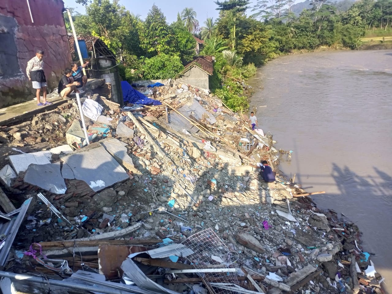 MENGAIS SISA: Warga mencari sisa barang yang bisa diselamatkan di atas puing-puing bangunan ruko yang hancur terseret amukan banjir bandang.