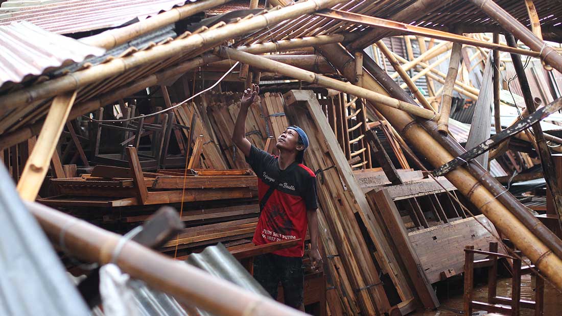 BENCANA LAGI: Warga berada di dalam bangunan tempat usaha yang rusak akibat diterjang angin kencang di Jalan Imogiri Timur, Bantul, kemarin (30/3). Puluhan bangunan rusak akibat tertimpa pohon yang roboh. Tercatat juga puluhan pohon dan baliho ambruk. (GU