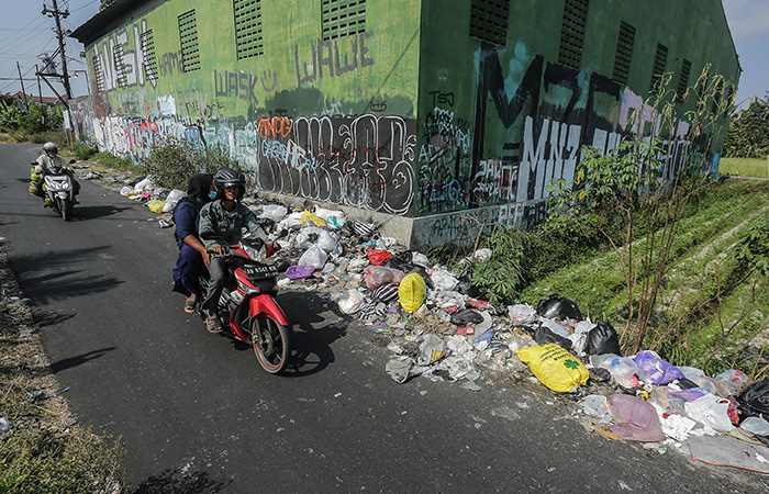 MENUMPUK: Pengendara motor melintasi tumpukan sampah di kawasan Mejing Kidul, Ambarketawang, Gamping Selasa (5/9/23). ELANG KHARISMA DEWANGGA/RADAR JOGJA