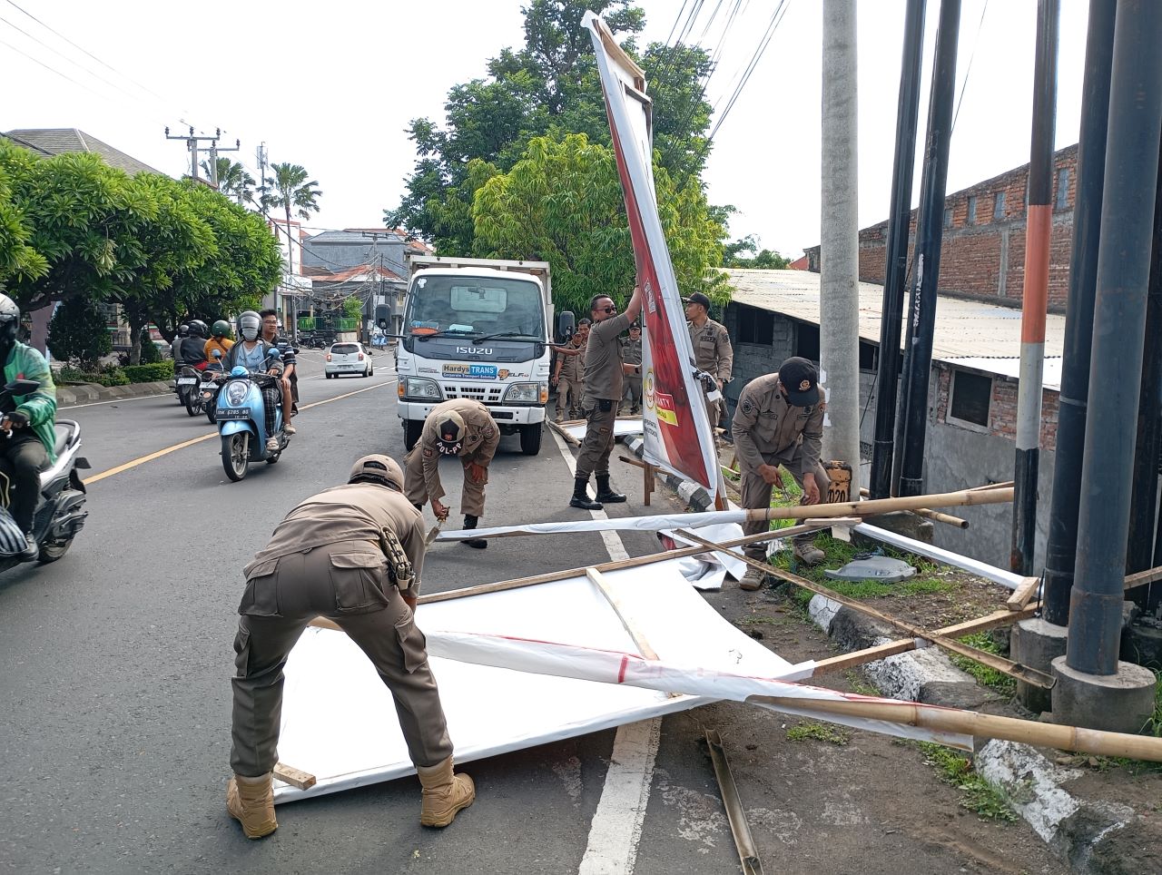 PEMBERSIHAN APK: Proses pembersihan Alat Peraga Kampanye (APK) yang masih terpasang di Jalan Surapati, Singaraja.