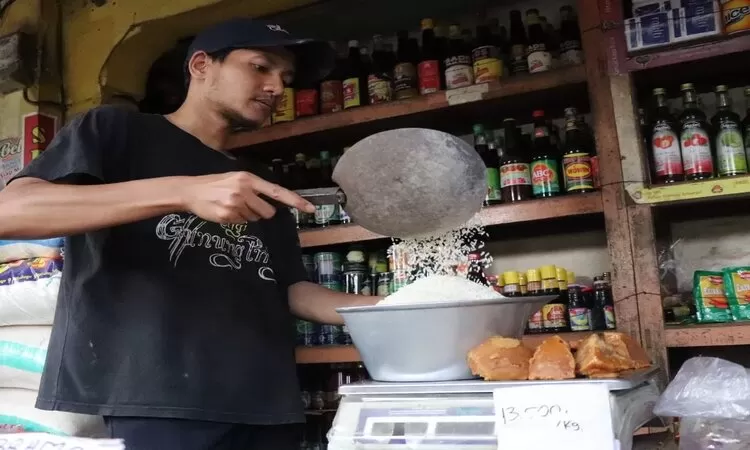 Pedagang beras Pasar Ngemplak, Tulungagung sedang menimbang barang dagangannya.