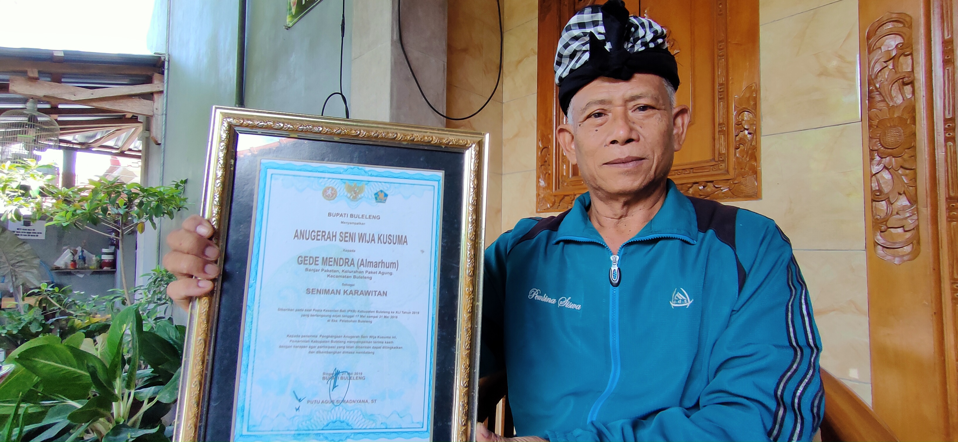 PENGHARGAAN: Putu Mahendra yang juga keponakan Gede Mendra, menunjukkan penghargaan Wija Kusuma dari Pemkab Buleleng yang diberikan kepada mendiang Gede Mendra,