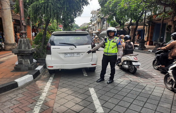Polisi menertibkan kendaraan yang parkir sembarangan di Jalan Gajah Mada Denpasar.